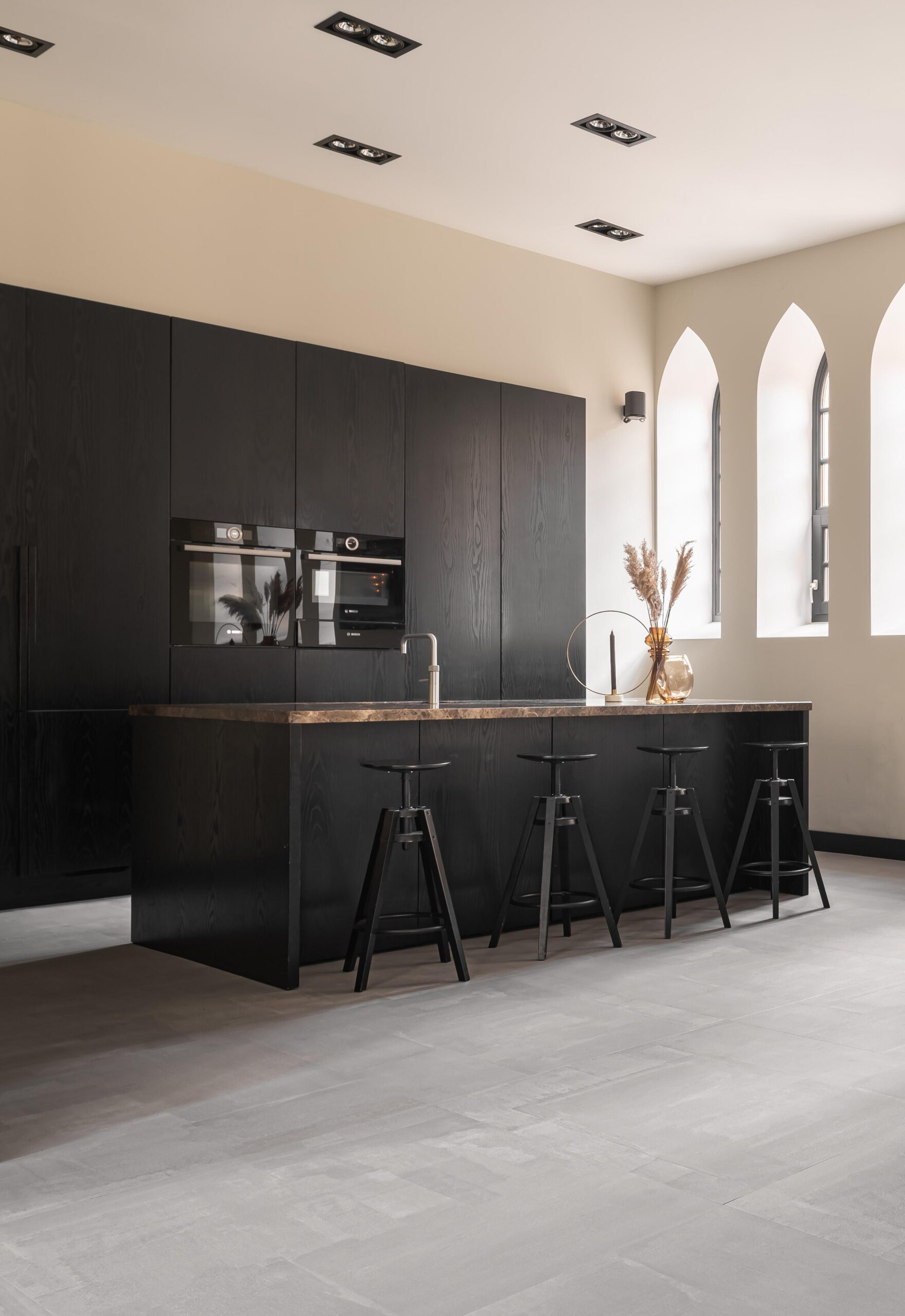 LVT-tegels met een lichte steenlook in een keuken met donkere kasten en hoge boogramen