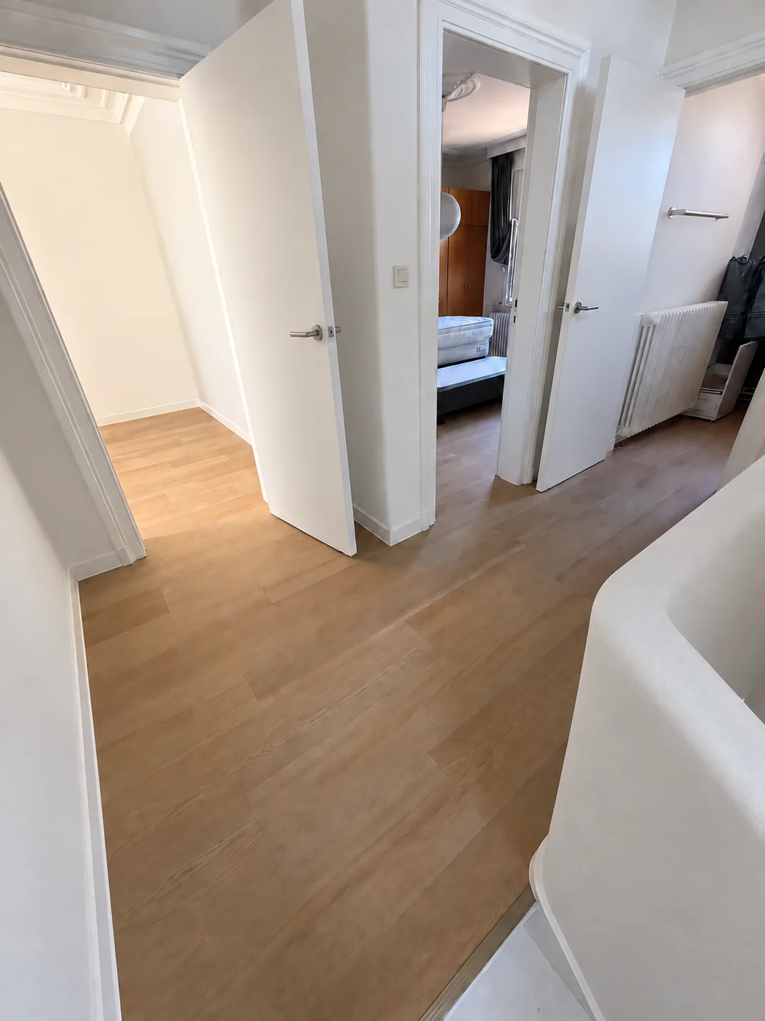 Rechte vloerplanken in een warme houttint, doorlopend van de overloop naar de aangrenzende kamers